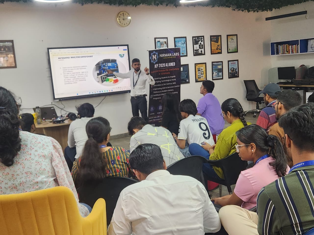A mentor explaining an Arduino microcontroller slide to students in a lab classroom